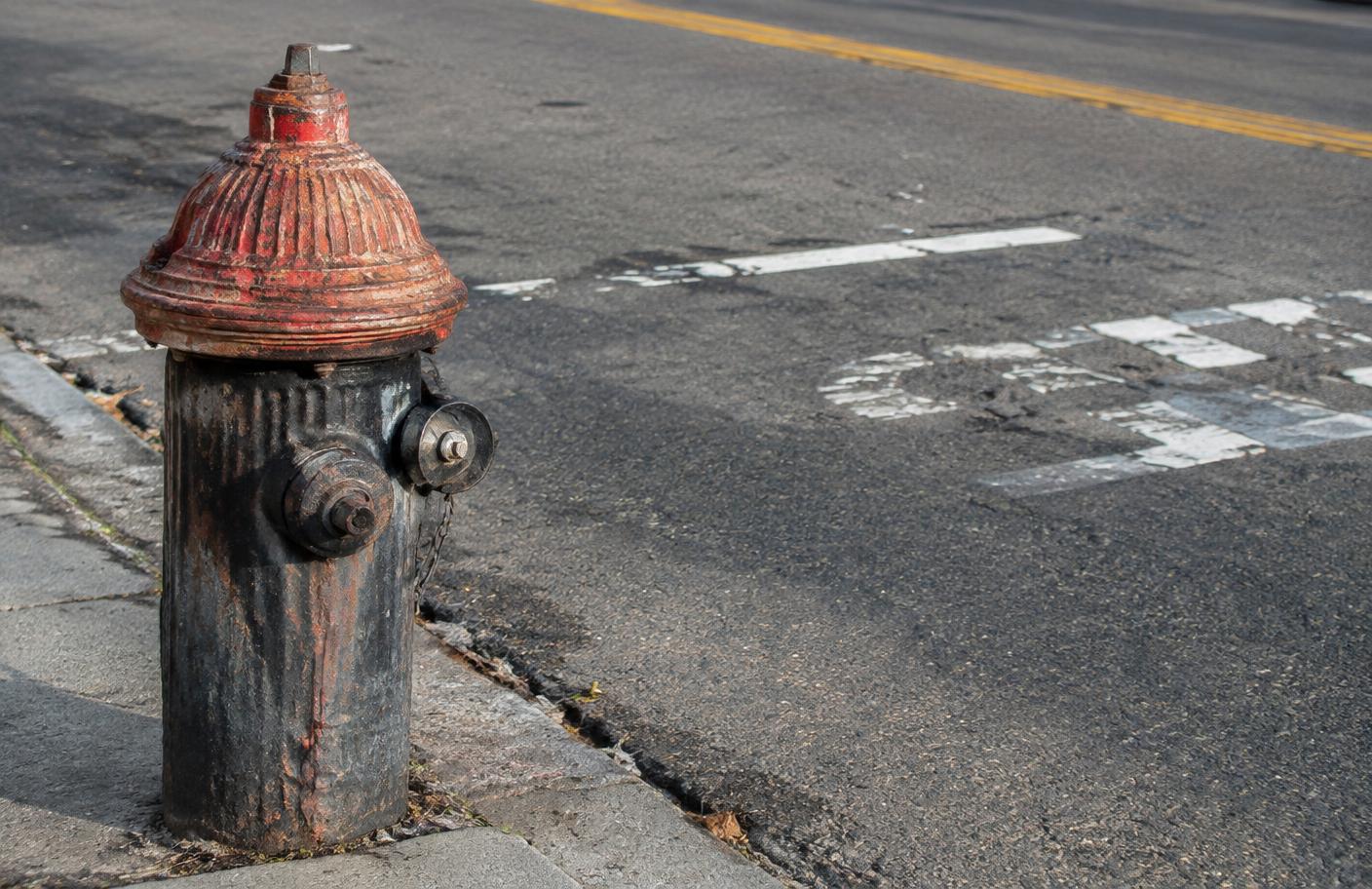 A weathered fire hydrant at the edge of a town street